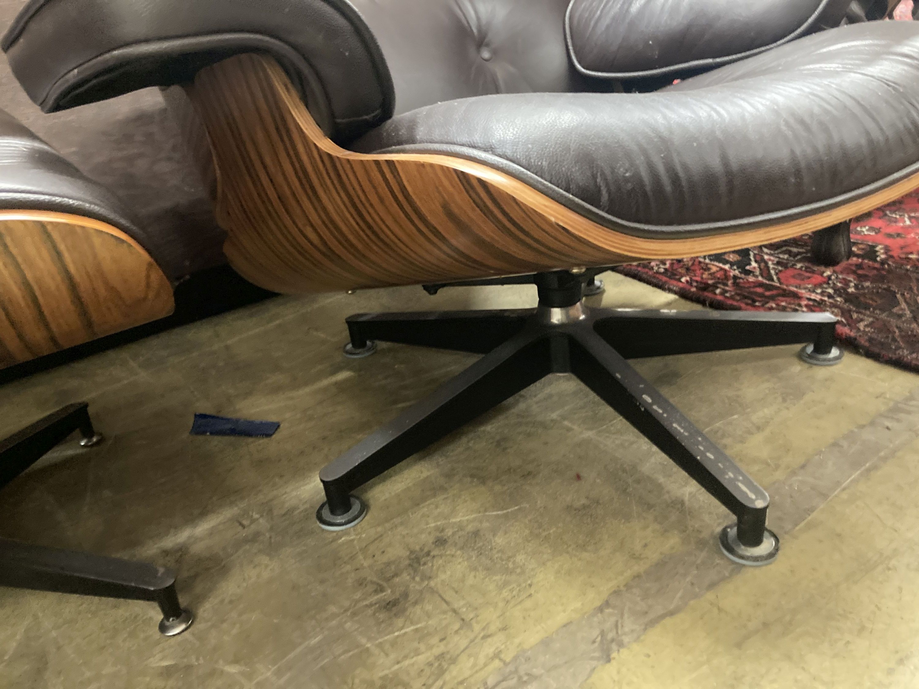 An Eames style modern buttoned dark brown leather swivel chair, width 92cm, depth 74cm, height 78cm and matching stool